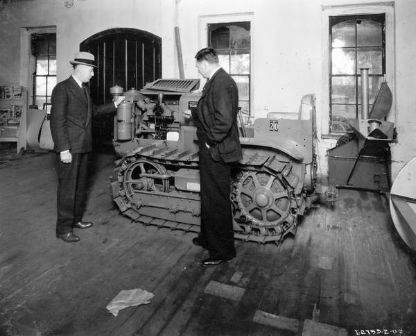 Two salesmen examining the features of a  McCormick-Deering T-20 TracTracTor (crawler tractor) at an International Harvester dealership.
