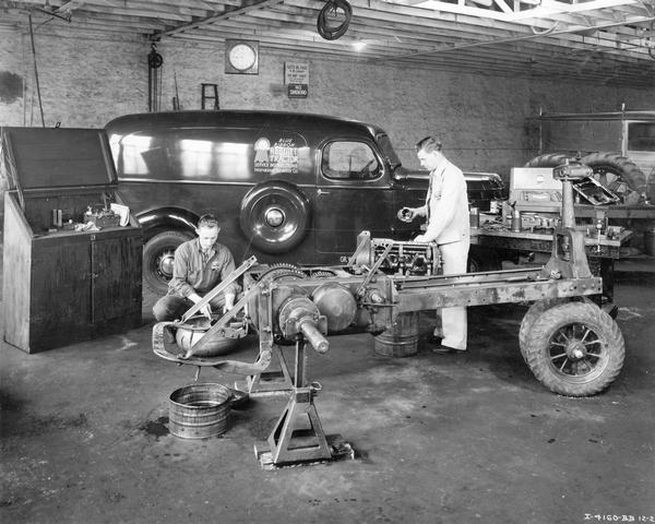Two service technicians inspecting parts from a disassembled Farmall tractor. The men are taking part in International Harvester's blue ribbon rebuilt tractor instruction service at the company's Topeka branch house.  An International D-Series panel service truck is in the background.