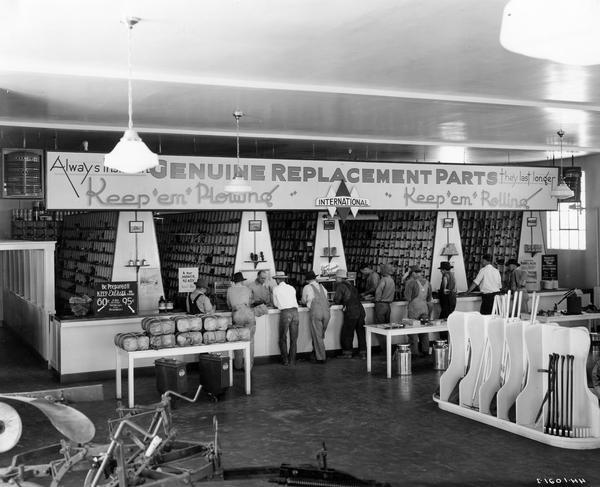 Farmers lined up along the parts counter of the Snake River Equipment Company, an International Harvester dealership. The store was managed by George Watkins.