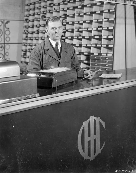 Man at the parts counter of an International Harvester dealership owned by the Great Lakes Supply Corp.