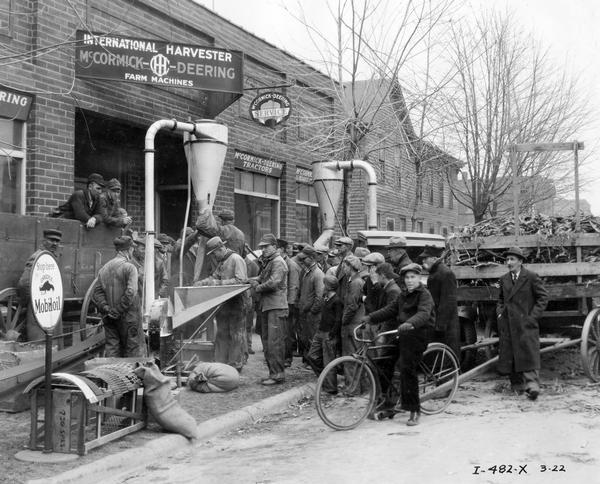 Farmers gathered for a hammer mill demonstration at the storefront of Neff Implement Co., an International Harvester dealership.