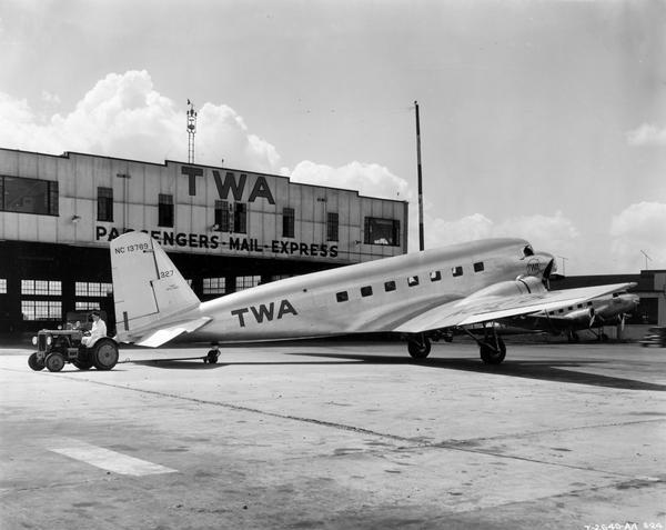 Worker moving Trans World Airlines DC-3 (DC-2?) airplane with an International industrial tractor outside the TWA hangar at Chicago's Municipal Airport (later Midway). The tractor was owned and operated by American Airlines.