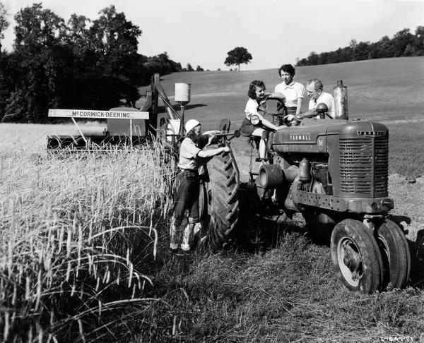 Dan Downey, International Harvester blockman from Philadelphia, teaches three women how to operate a Farmall M tractor and a McCormick-Deering harvester-thresher (combine). The women are members of the Red Cross Motor Corps from Paoli and W. Chester, PA. The women took part in a variety of jobs on Herbert Hill's angus farm. Pictured here are (L to R): Mary G. Baldwin, Mrs. P.F. Smith and Mrs. S.E. Smith. The women were taking part in International Harvester's "Tractorette" program. The company announced the program in 1942. It was intended to address the farm labor shortage created by U.S. war mobilization. The plan called for local dealers to offer free training for thousands of farm women and girls in the operation of tractors and other farm machinery.