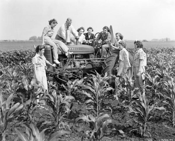 Instructor Mr. Schweitzer reviewing the operation of a Farmall M tractor with a group of women. The women are (L to R): Donna Mehaffy, Oakville; Marian Hultgren, Mediapolis; Susanne Wilson, Mediapolis; Helen Creelman, Mediapolis; Rosemary Yoder, Oakville; Cynthia Jantz, Oakville; Helen Jackson, Sperry; and Lois Wilson, Morning Sun. The women are taking part in International Harvester's "Tractorette" program. The company announced the program in 1942. It was intended to address the farm labor shortage created by U.S. war mobilization. The plan called for local dealers to offer free training for thousands of farm women and girls in the operation of tractors and other farm machinery.