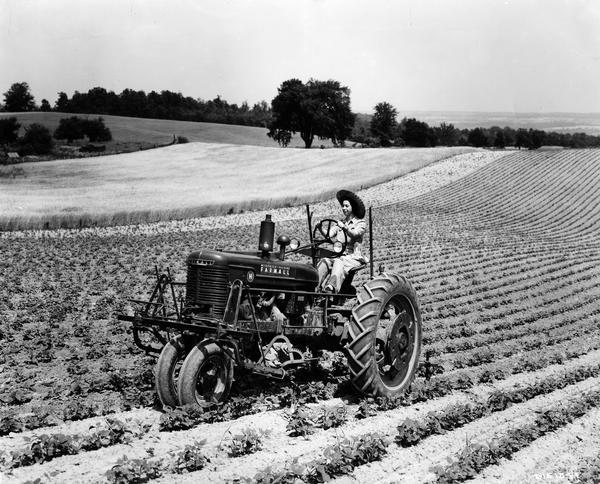 Mrs. Elizabeth Lancton cultivating with a Farmall H tractor on the 105 acre farm of Cliff Lee. Mrs. Lancton attended classes offered by Fred R. Walkley, proprietor of the Walkley Farm Equipment Co., who conducted Tractorette schools at his stores in Castile and Perry, New York. The company announced the "Tractorette" program in 1942. It was intended to address the farm labor shortage created by U.S. war mobilization. The plan called for local dealers to offer free training for thousands of farm women and girls in the operation of tractors and other farm machinery.