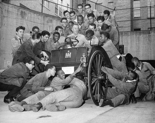 Several young men (possibly auto shop students?) posing with a 1907 International Auto Wagon.