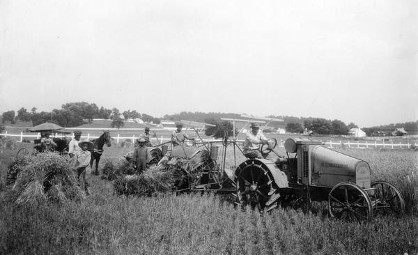 Farmers harvesting wheat with an International 8-16 HP kerosene tractor and two Deering seven foot binders on the farm of W.P. Ridley in Maury County. Three African American farm hands are binding and stacking bales. An original letter attached to the back of the image notes that the workers cut eighty acres of wheat within thirty hours using 30 gallons of kerosene and about 5 quarts of cylinder oil, with a total cost per acre of about eleven and three-fourths cents for fuel.