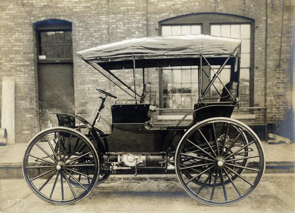 International Auto Buggy parked on a street outside a brick building. The back of the print is stamped "Experimental Department, General Office, rec'd June 5, 1907."