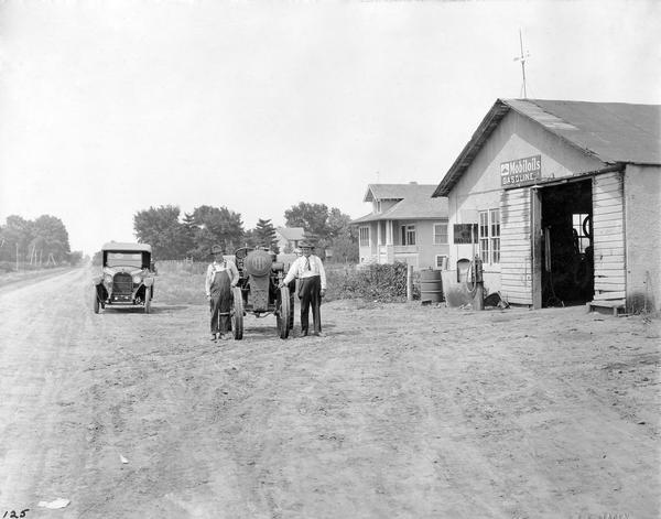 Farmer L.L. Harvey (right) and his son Chester posing with a Titan 10-20 tractor in front of a rural service station.