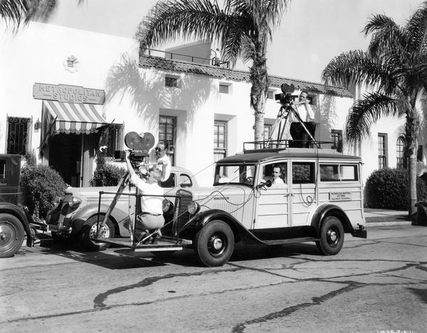 Four-man crew demonstrating their filming techniques with an International C-1 wood-paneled ("woody") station wagon in front of Metropolitan Studios. The crew worked for Metropolitan Industrial Pictures.