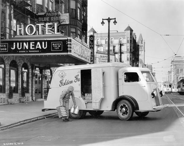 Milkman delivering milk to the Hotel Juneau. The International C-300 truck was owned by Golden Guernsey Dairy Co. A sign above the hotel awning advertises Pabst Blue Ribbon beer.