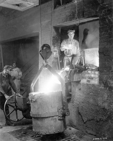 Workers pouring alloy into a stream of iron in the foundry of International Harvester's Tractor Works. The factory was located at 2600 West 1st Blvd.