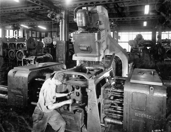 Worker drilling the main frame of a TracTracTor (crawler tractor) at International Harvester's Tractor Works. The factory was located at 2600 West 1st Blvd.
