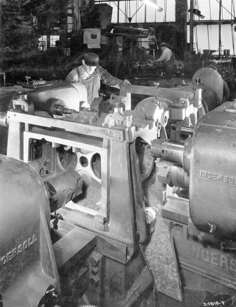 Worker using machines to mill gear centers of a TracTracTor (crawler tractor) main frame at International Harvester's Tractor Works.