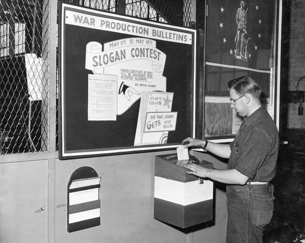 Factory worker Bill Niskala submitting an entry for a war production slogan contest conducted by International Harvester's Production Drive Committee. The contest was intended to produce an official war production slogan to stimulate employees to greater production. This suggestion box was located in an International Harvester factory producing 20 millimeter guns for the U.S. military.