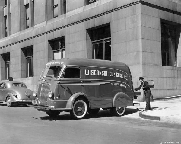 Iceman delivering a block of ice from an International D-300 streamlined truck to an office building in downtown Milwaukee. The man worked for the Wisconsin Ice and Coal Company.
