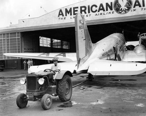 Airport worker towing an American Airlines airplane with an International I-12 industrial tractor at the Newark airport.