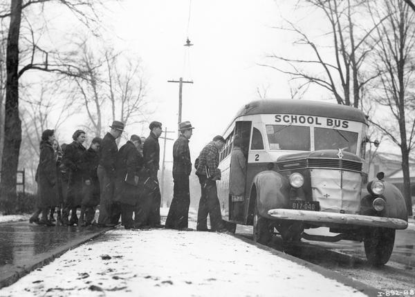 Students lining up to board an International D-40 school bus on a snowy afternoon. The bus featured a 235-inch wheelbase with a Rex-Watson, 49-passenger body.