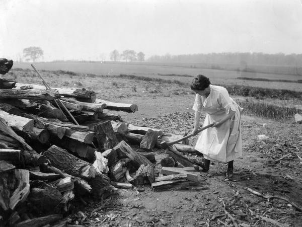 Woman chopping wood on the farm of E.A. Bancroft.