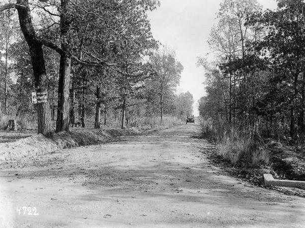 Car coming down a rural dirt road. Caption reads: "A view on Houston and Oklona Pike. Chickasaw Co. has over 100 miles of fine pikes and building more." A Coca-Cola sign is nailed to a tree in the left foreground.