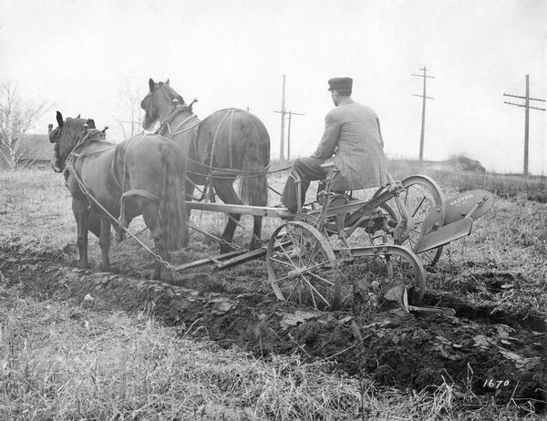 Man operating an unidentified Oliver plow, with no. 82 moldboard, drawn by two horses. The photograph was taken for, or compiled by International Harvester's Agricultural Extension Department.