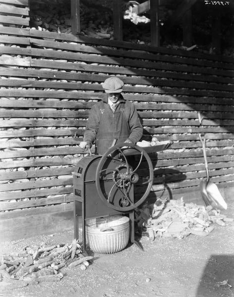 Man feeding corn cobs into an International all steel one-hole corn sheller.