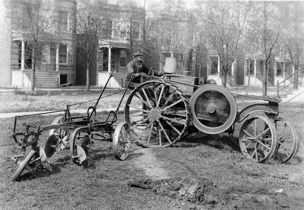 Man using a Mogul 10-20(?) tractor with attached plow to plow garden lots in an urban residential neighborhood at Jackson Blvd. and 54th Street. "This outfit was used for plowing garden plots in Chicago. The possibility of short turns made it practical for use in plowing small tracts."