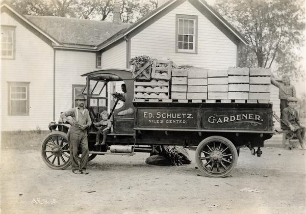 Gardener Edward Schuetz and four sons posing with his delivery truck loaded with vegetables for market. The truck is not an International model.