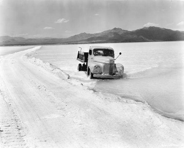 International truck making its way through the Salduro Marsh of the Bonneville Salt Flats near Wendover on the Utah-Nevada border. The original caption reads in part: "In the raw state the potash occurs as a brine found in the clay stratum underlying the Bonneville Flats. Solar evaporation in numerous drying ponds produces a mixture of crystalline sodium and potassium salts which are separated by flotation in the plant of Bonneville, Ltd., near Wendover...To obtain the brine, Bonneville, Ltd., had dug some forty miles of ditches, fifteen feet deep, into which the brine seeps from the pores of the clay stratum that underlies the salt flats. From the distributing ditches the brine is lifted to drying ponds."
