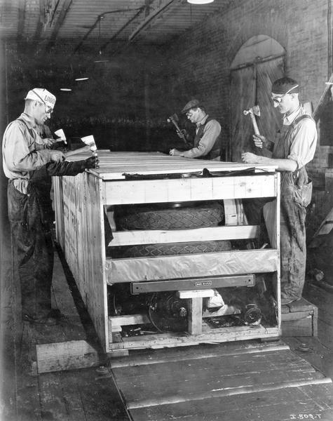 Four workers crating up International motor trucks for export shipment at International Harvester's Springfield Works (factory). One of the men is wearing a hat with the word "union" clearly visible.