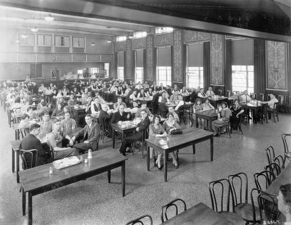 Male and female factory and office workers sitting in the cafeteria at International Harvester's West Pullman Works.