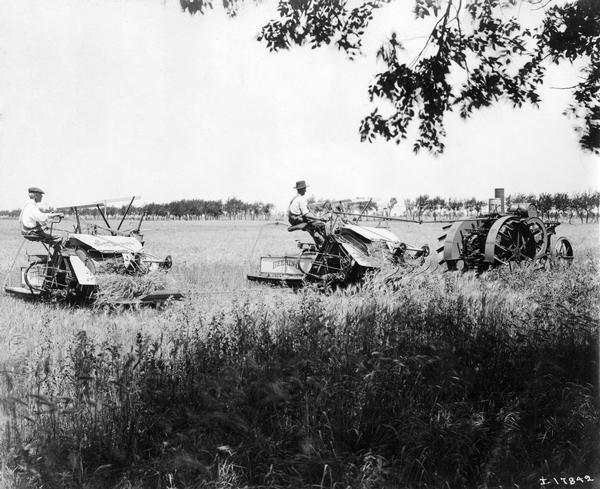 Two men are using an International Harvester Mogul 10-20 HP tractor to pull the two Deering New Ideal binders they are riding in a field during 10-20 tractor development and application testing.