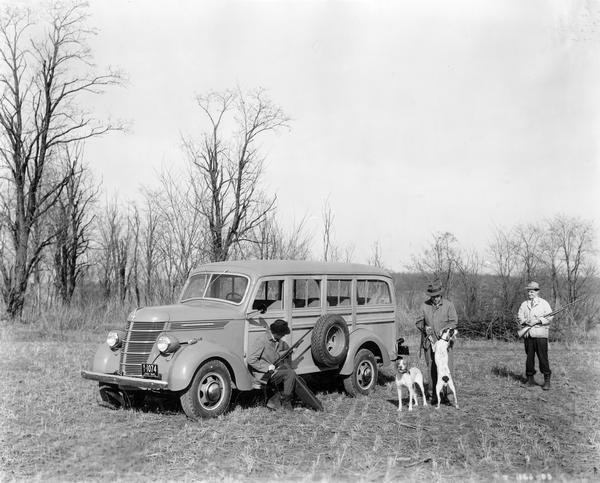Three sportsmen with shotguns and hunting dogs around an International D-15-M station wagon ("woody"). The photograph may have been staged for advertising purposes.
