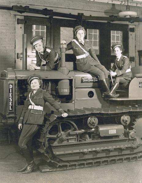 Four female "traffic officers" posing with an International diesel TD-40 TracTracTor (crawler tractor) in preparation for a tractor road show.