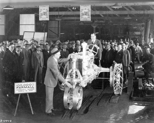 Cyrus McCormick III riding the 100,000th Farmall tractor off the Farmall Works assembly line. The tractor was painted silver to mark the occasion. At the front of the line is Superintendent E.H. Sohner.