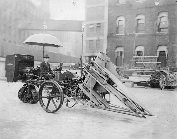 Engineering photograph of an experimental motor cultivator with a mounted ensilage cutter(?). A Deering grain binder is in the background.