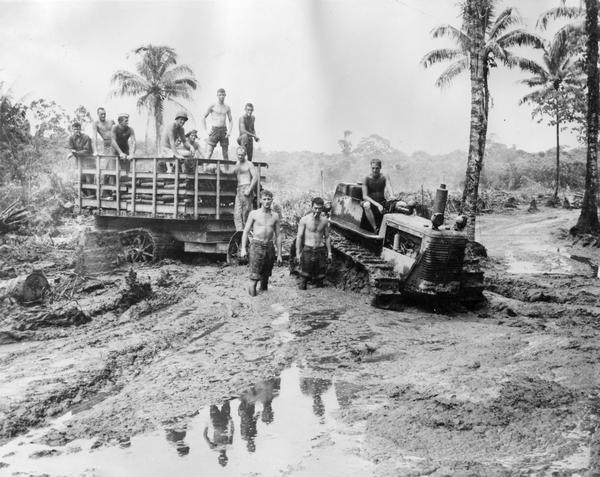 U.S. Marines using an International Harvester TracTracTor to transport supplies through muddy soil. Original caption reads: "Soil, principally sandy-mud, and daily rain storms were tough on the Marines during their first days on Bougainville. Jeeps and trucks were unable to get through to the front lines with food and ammunition and International diesel crawlers and trailers had to be used until the engineers and Seabees could surface roads with coral from the sea." Official U.S. Marine Corps photo.