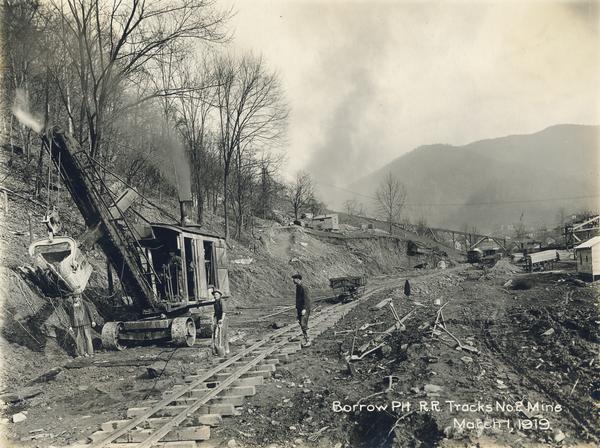 Workers digging a "borrow pit" for no. 2 mine with a steam shovel. The men are standing along a set of narrow gauge railroad tracks. Benham was a "company town" created by International Harvester for the workers of the Wisconsin Steel Company. Wisconsin Steel was a subsidiary of International Harvester and operated coal mines at Benham.
