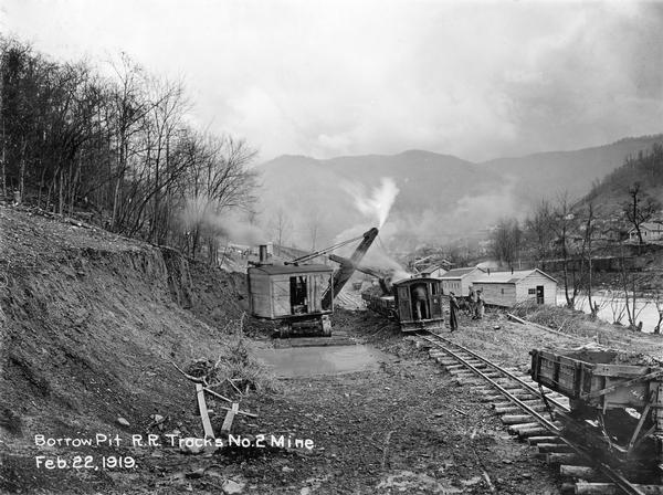 Workers using a steam shovel to dig a "borrow pit" for the no. 2 mine. The shovel is loading soil onto a rail car on a narrow gauge railroad track. Benham was a "company town" created by International Harvester for the workers of the Wisconsin Steel Company. Wisconsin Steel was a subsidiary of International Harvester and operated coal mines at Benham.
