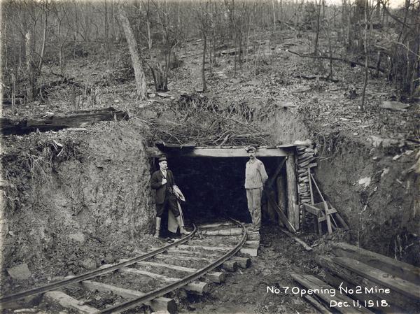 Two men, at least one of them a miner, standing in front of the no. 7 opening to the no. 2 mine. Benham was a "company town" created by International Harvester for the workers of the Wisconsin Steel Company. Wisconsin Steel was a subsidiary of International Harvester and operated coal mines at Benham.