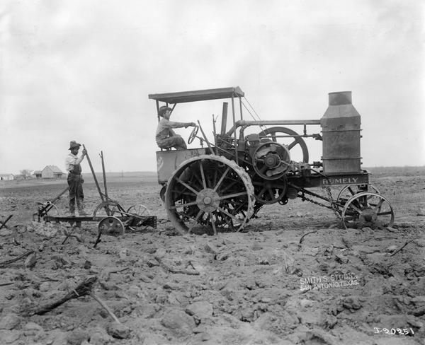 Farmers plowing arid land with a Rumely "Oil Pull" kerosene tractor and a breaking plow. Photograph taken by "Smith's Studio, San Antonio, Texas" for the International Harvester Company.