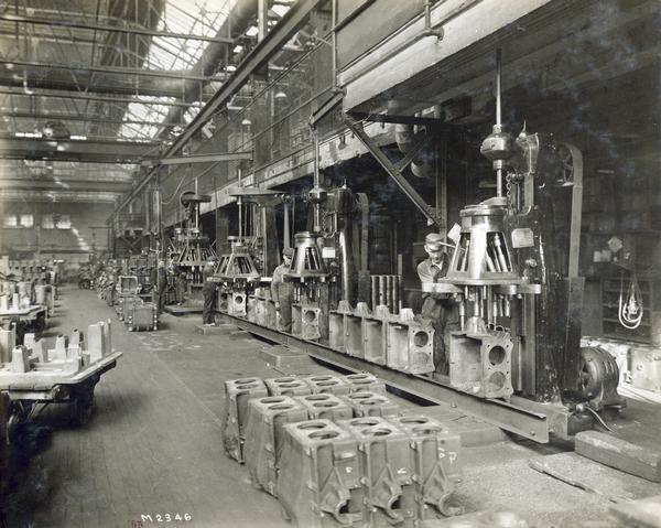 Factory workers machine tractor engine blocks at International Harvester's Milwaukee Works. The factory was owned by the Milwaukee Harvester Company before 1902.