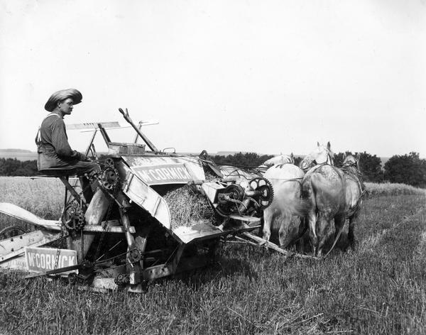 Farmer harvesting grain with McCormick grain binder built in 1883. Original caption reads: "The frame was made entirely of wood, iron being used only for gears, braces, etc. McCormick's first twine binder was built in 1881 — fifty years after his invention of the reaper. After that time, improvements consisted chiefly in the use of better-grade materials to provide lighter draft and greater durability."