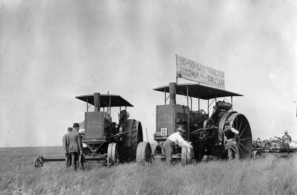 Men tending to two Aultman and Taylor tractors at the Winnipeg tractor contest in Canada. One of the tractors is a 30-60 gas tractor.