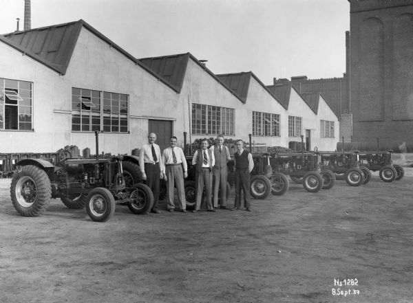 Men standing with Farmall 12 tractors ready for shipment at International Harvester's Neuss Works in Germany.