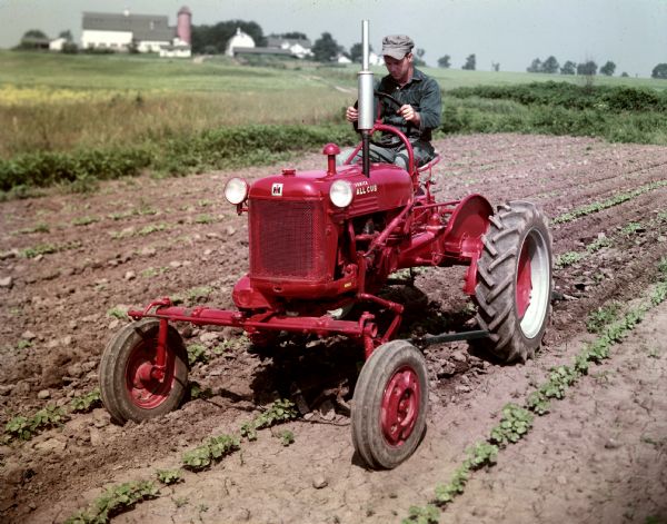 Farmer cultivating a field with a McCormick Farmall Cub tractor. The color photograph was likely taken for advertising purposes at Hinsdale Farm, near International Harvester's experimental farm.