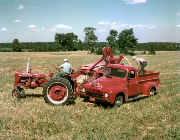 Farmers harvesting grain with a McCormick Farmall Super C tractor, combine (harvester-thresher) and International LM-120 truck. The McCormick Farmall Super C tractor was produced from 1951-1954. International LM-120 trucks were produced between 1949 and 1953.