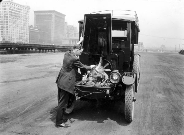 Man inspecting the engine of an International Model H truck. The 201 cubic inch H engine featured an L-head design, with three main bearings and forced lubrication, and a centrifugal water pump.