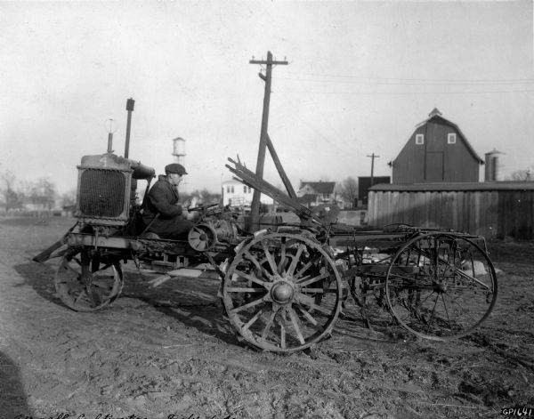Engineering photograph of a man testing an  experimental motor cultivator. Original caption reads: "In this job the cultivator is set farther ahead than in previous developments, and is carried on its own wheels. This outfit was heavy, awkward to handle, and evidently did not get past the experimental stage. Another objection was that the operators back was right up against the motor--in this respect the job was a hot one."