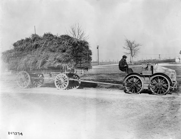 Worker hauling a wagon loaded with hemp using a an experimental four-wheel drive International 8-16 tractor.